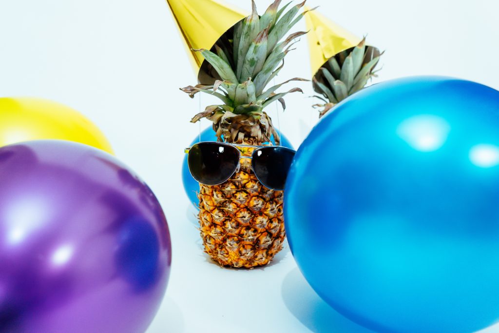 pineapple with party hat and balloons